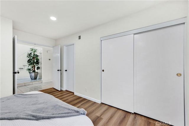 bedroom featuring wood finished floors, recessed lighting, a closet, and baseboards