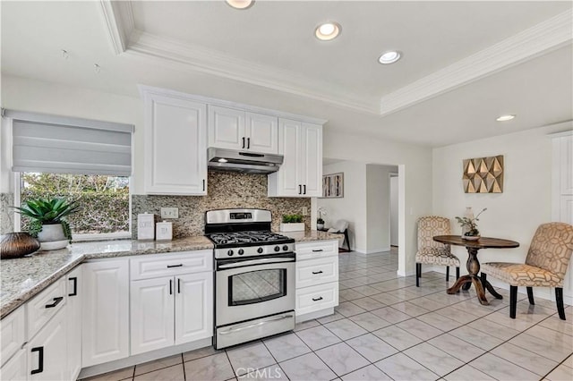 kitchen with stainless steel range with gas cooktop, a raised ceiling, under cabinet range hood, backsplash, and white cabinetry