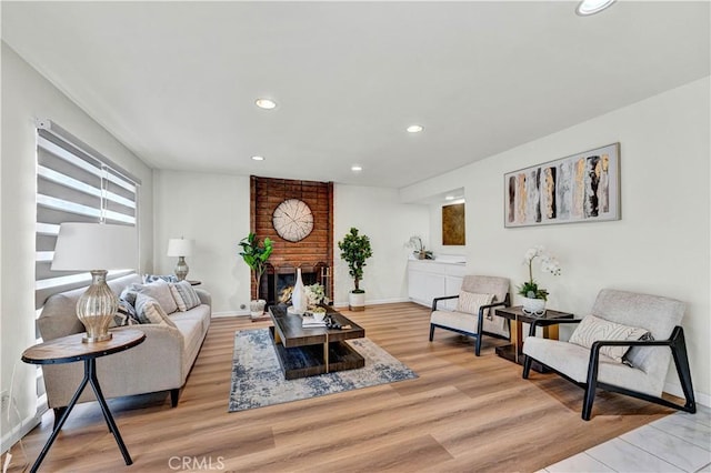 living area with recessed lighting, a fireplace, light wood finished floors, and baseboards
