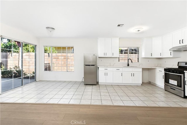 823 E 3rd St, Pomona, CA 91766 - kitchen with stainless steel appliances, under cabinet range hood, light countertops, a sink, and white cabinetry
