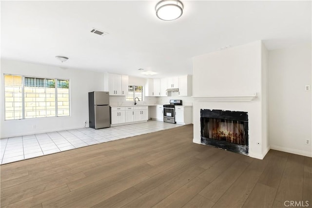 823 E 3rd St, Pomona, CA 91766 - unfurnished living room featuring light wood finished floors, a sink, a lit fireplace, and baseboards