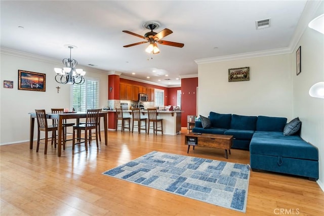 living area featuring a ceiling fan, light wood-style floors, ornamental molding, a chandelier, and baseboards