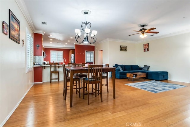 dining room featuring light wood-style flooring, a ceiling fan, crown molding, a chandelier, and recessed lighting