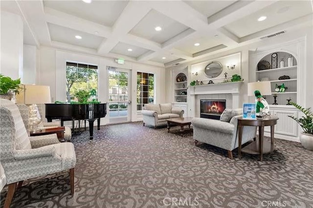 living room featuring built in shelves, carpet floors, coffered ceiling, a glass covered fireplace, and beamed ceiling