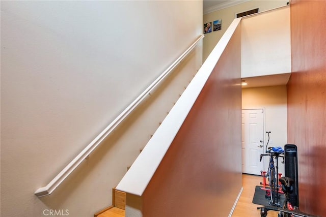 stairs featuring wood finished floors, crown molding, and baseboards