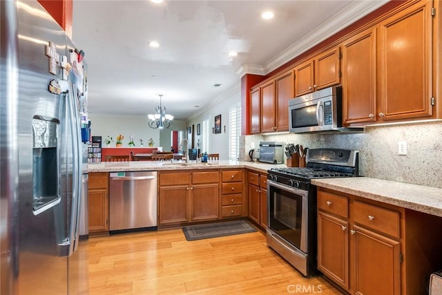 kitchen with appliances with stainless steel finishes, crown molding, a sink, light wood-type flooring, and brown cabinets