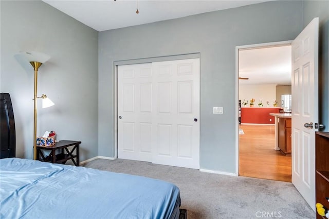 bedroom featuring light colored carpet, a closet, and baseboards