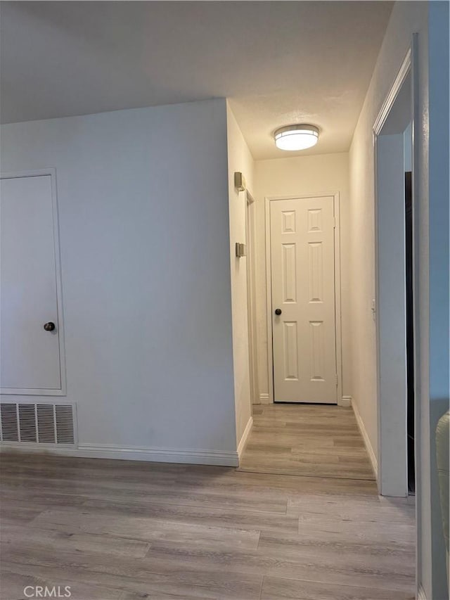 hallway with light wood-type flooring and baseboards