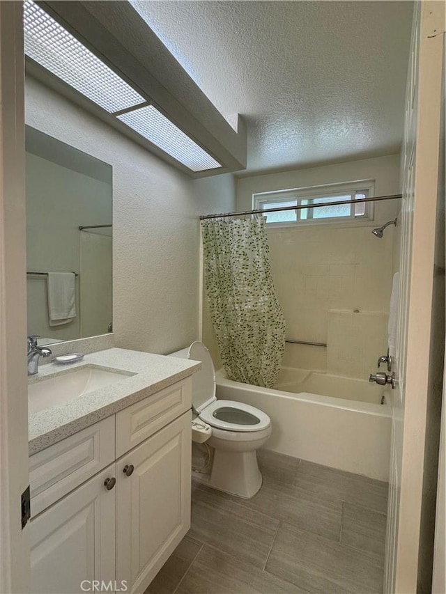 full bathroom featuring toilet, vanity, shower / tub combo with curtain, and a textured ceiling