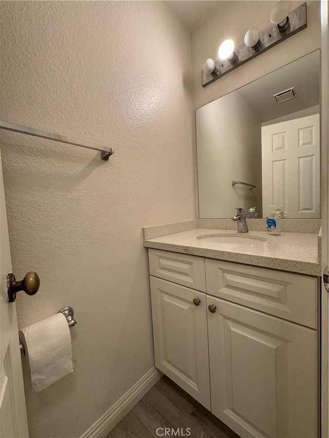 bathroom featuring wood finished floors, vanity, and baseboards