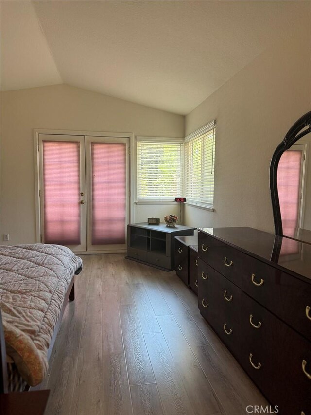 bedroom featuring vaulted ceiling, access to exterior, and light wood-style flooring