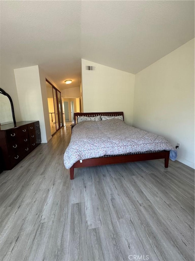 bedroom featuring wood finished floors, vaulted ceiling, and baseboards