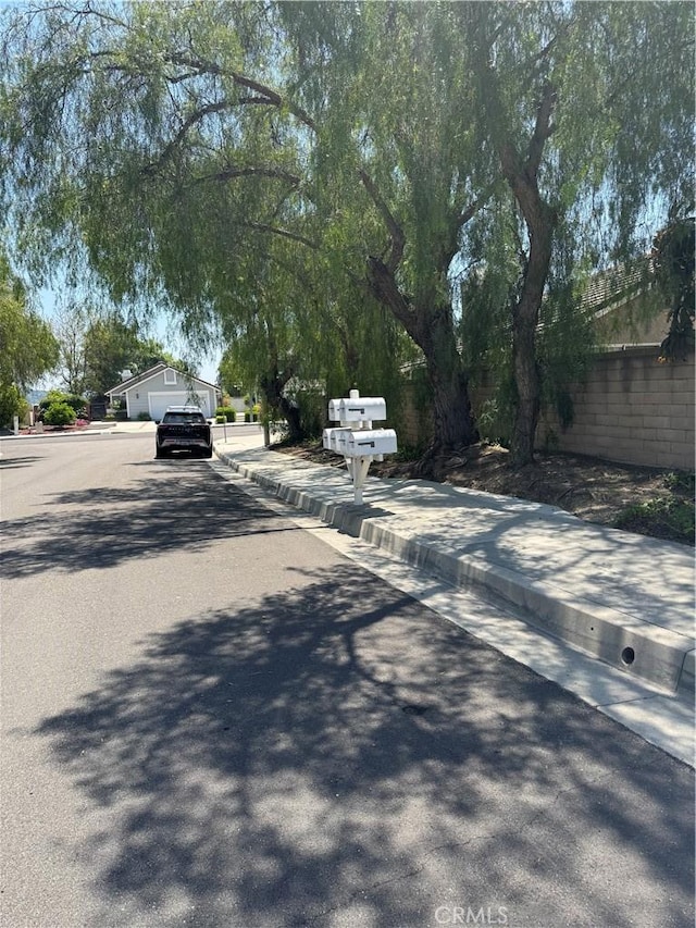 view of asphalt road with curbs and sidewalks