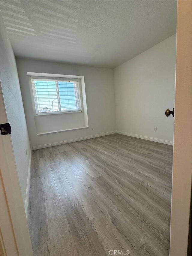 empty room with wood finished floors, baseboards, and a textured ceiling