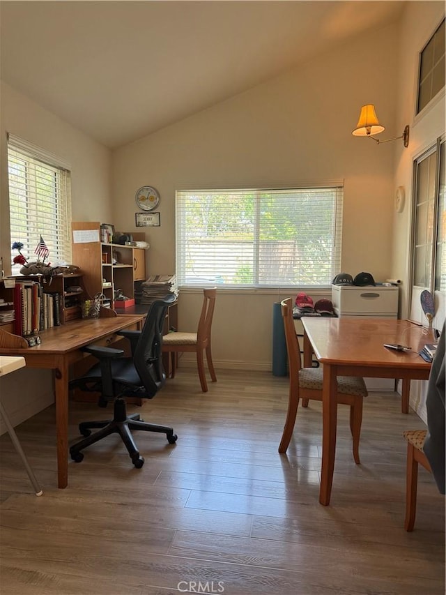 home office with vaulted ceiling, healthy amount of natural light, wood finished floors, and baseboards