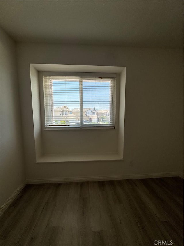 unfurnished room featuring dark wood-type flooring and baseboards