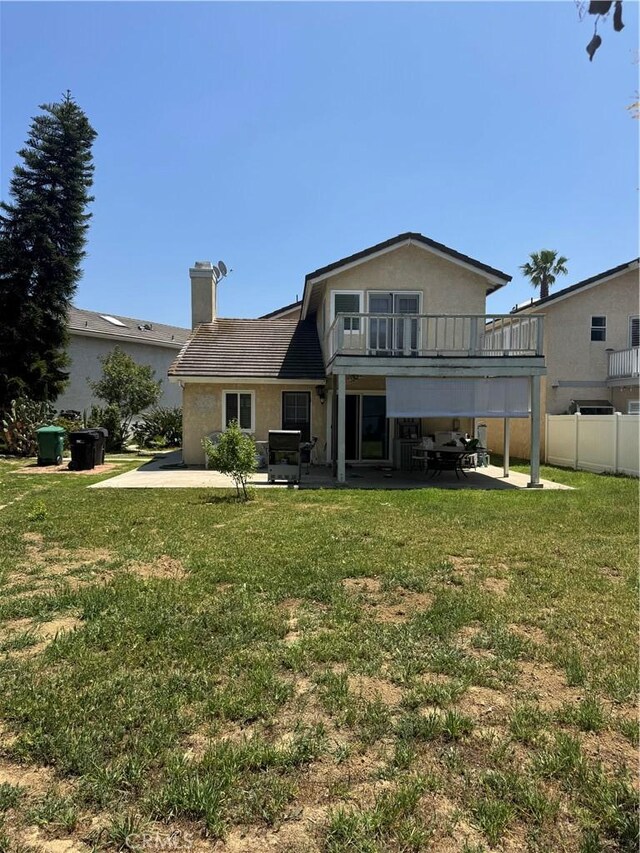 rear view of property with a patio area, a chimney, stucco siding, and a balcony