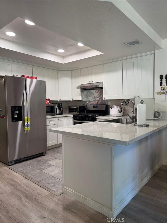 2801 Woodview Ct, Walnut, CA 91789 - kitchen with stainless steel appliances, under cabinet range hood, a tray ceiling, a peninsula, and white cabinets
