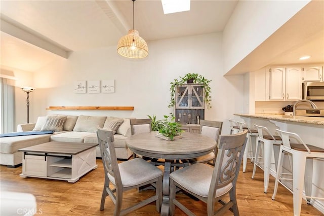 dining area with light wood-style flooring and beam ceiling