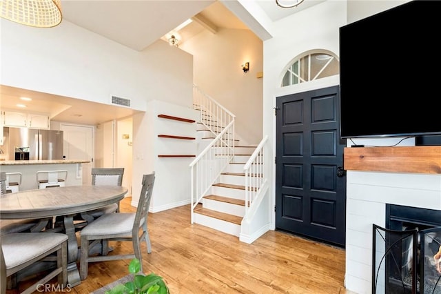 foyer with stairway, high vaulted ceiling, light wood finished floors, beamed ceiling, and baseboards