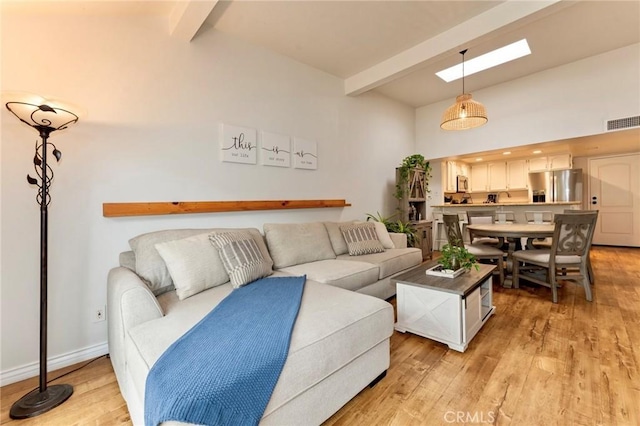 living area with a skylight, light wood-style floors, and baseboards