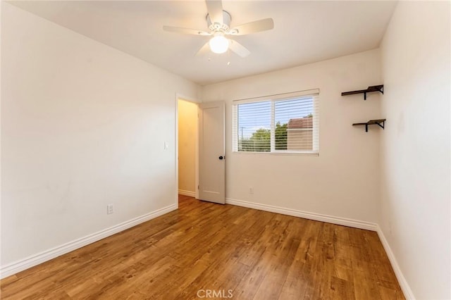 unfurnished room with wood finished floors, baseboards, and ceiling fan