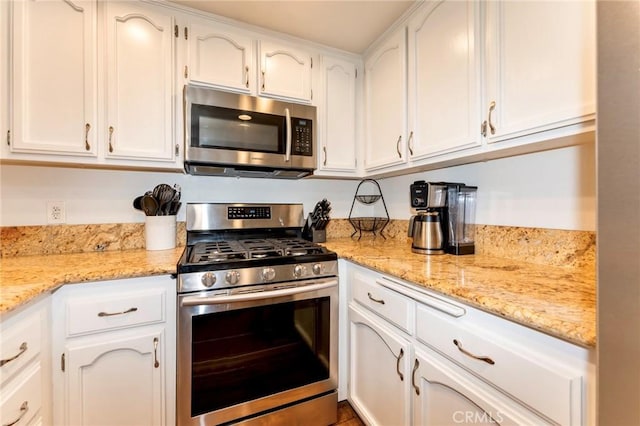 kitchen featuring appliances with stainless steel finishes, white cabinetry, and light stone countertops