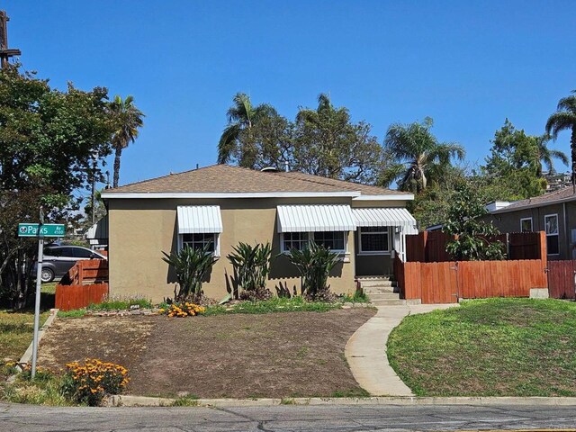 bungalow-style home featuring stucco siding, fence, entry steps, and a shingled roof