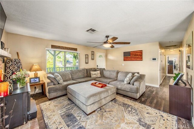 living room featuring wood finished floors, baseboards, ceiling fan, and a textured ceiling