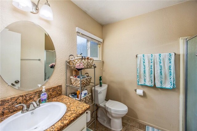 bathroom featuring toilet, tile patterned flooring, an enclosed shower, vanity, and a textured wall