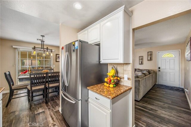 kitchen featuring freestanding refrigerator, dark wood-style flooring, white cabinetry, light stone counters, and decorative backsplash