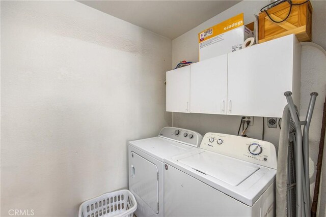 laundry area with independent washer and dryer and cabinet space