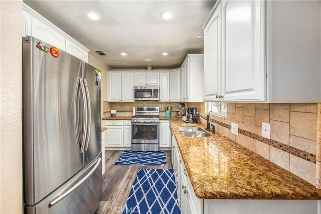 kitchen with appliances with stainless steel finishes, a sink, white cabinets, dark wood finished floors, and recessed lighting