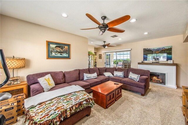 living room with a ceiling fan, light carpet, recessed lighting, and a glass covered fireplace