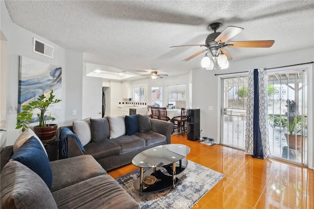 living area featuring a ceiling fan, a textured ceiling, and light tile patterned floors