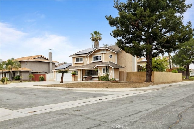 traditional home with fence, roof mounted solar panels, concrete driveway, stucco siding, and a garage