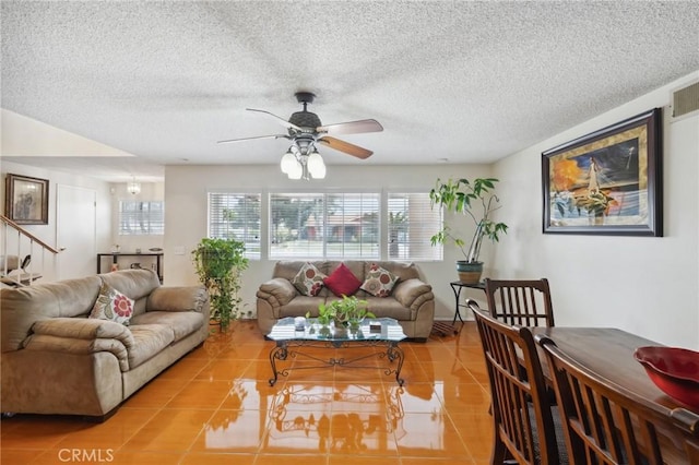 living room with healthy amount of natural light, ceiling fan, tile patterned flooring, and a textured ceiling