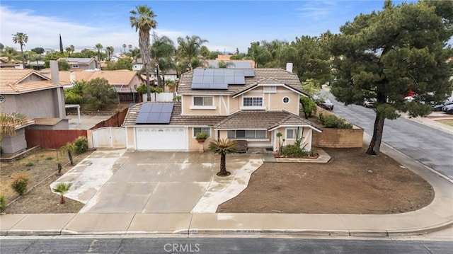 view of front of home with driveway, a tiled roof, solar panels, stucco siding, and fence