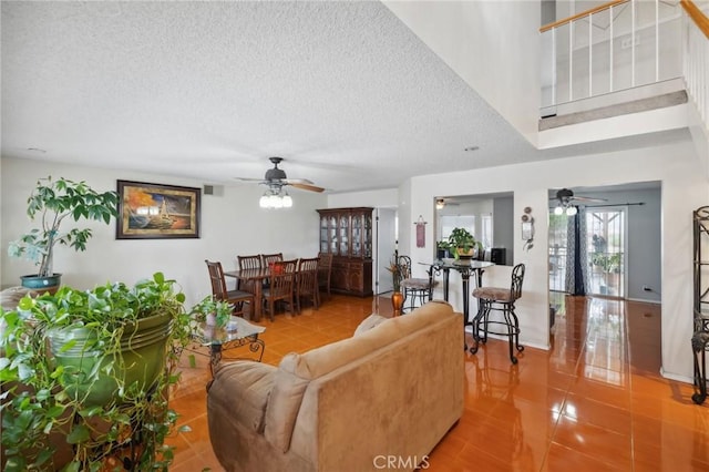 living area featuring ceiling fan, tile patterned flooring, and a textured ceiling