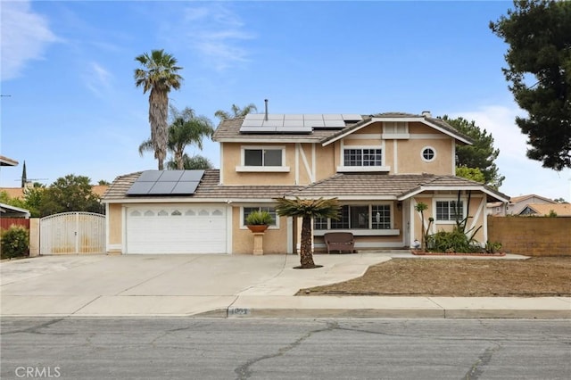 view of front facade featuring stucco siding, a gate, roof mounted solar panels, fence, and driveway