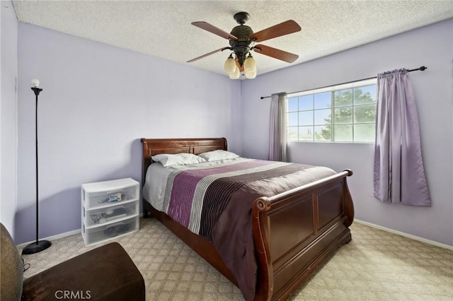 bedroom with ceiling fan, baseboards, a textured ceiling, and light carpet