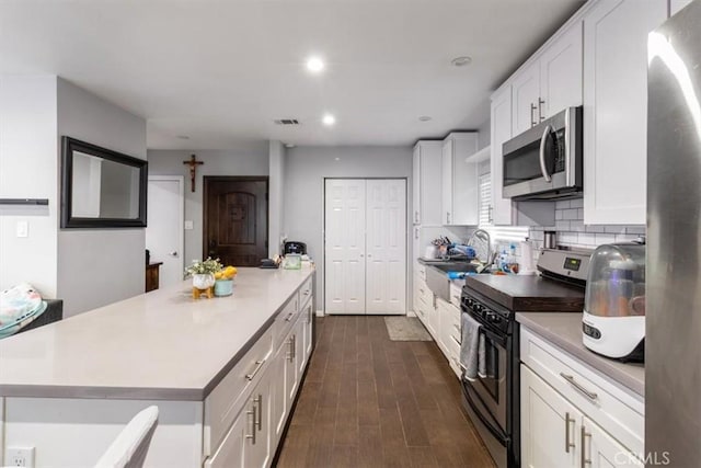 4034 Durfee Ave, Pico Rivera, CA 90660 - kitchen with appliances with stainless steel finishes, a sink, white cabinetry, dark wood finished floors, and a center island