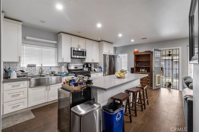 4034 Durfee Ave, Pico Rivera, CA 90660 - kitchen with appliances with stainless steel finishes, a sink, dark wood-style floors, a kitchen island, and a kitchen bar