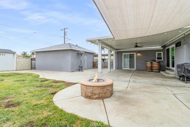 view of patio featuring an outdoor fire pit, an outbuilding, ceiling fan, and a grill