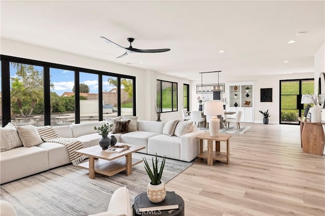 living room with a ceiling fan, plenty of natural light, light wood finished floors, and recessed lighting