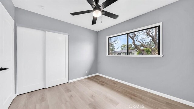 unfurnished bedroom with light wood-type flooring, baseboards, and a ceiling fan