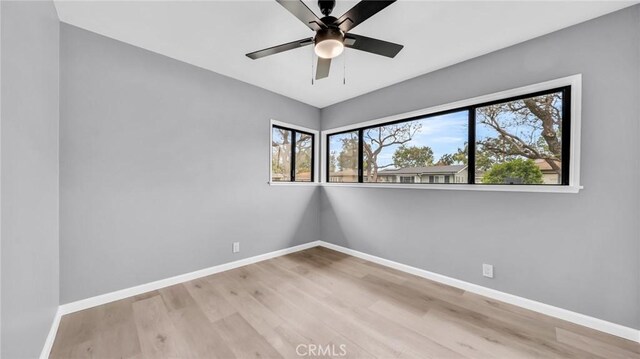 spare room featuring baseboards, wood finished floors, and ceiling fan
