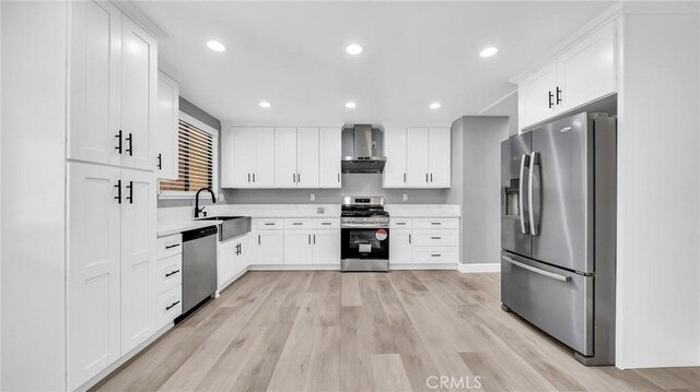 kitchen with stainless steel appliances, wall chimney range hood, recessed lighting, white cabinetry, and light countertops