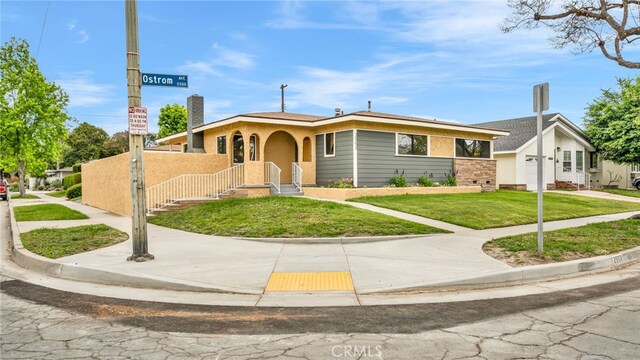 bungalow-style home with a front lawn, stucco siding, and a garage