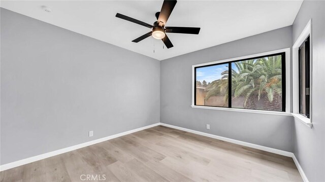 spare room featuring wood finished floors, a ceiling fan, and baseboards